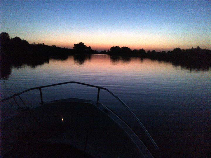 Een boot 's avonds met zonsondergang op het water vaart